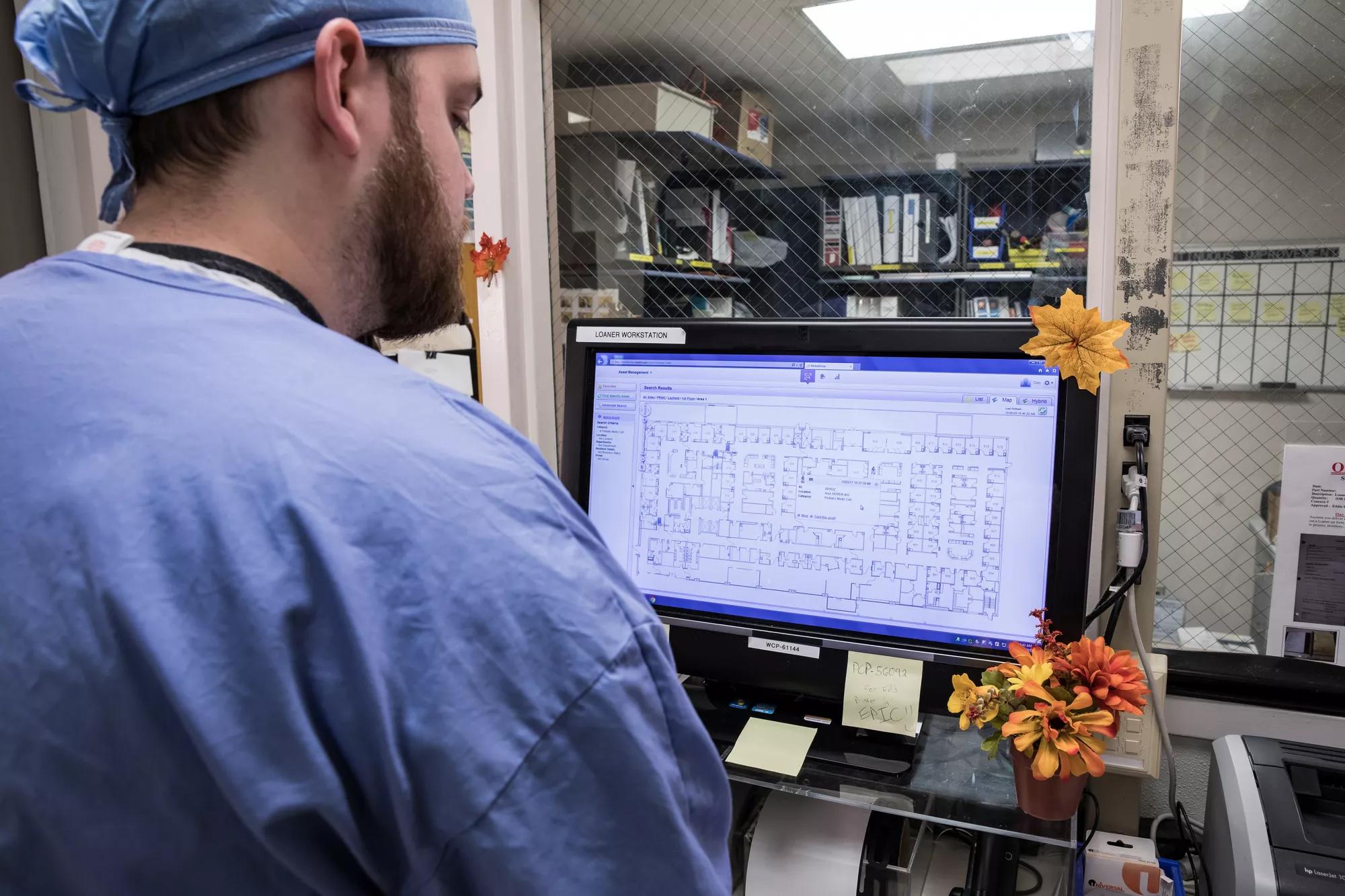 Healthcare worker viewing a computer screen to locate hospital equipment using Securitas's asset tracking. 