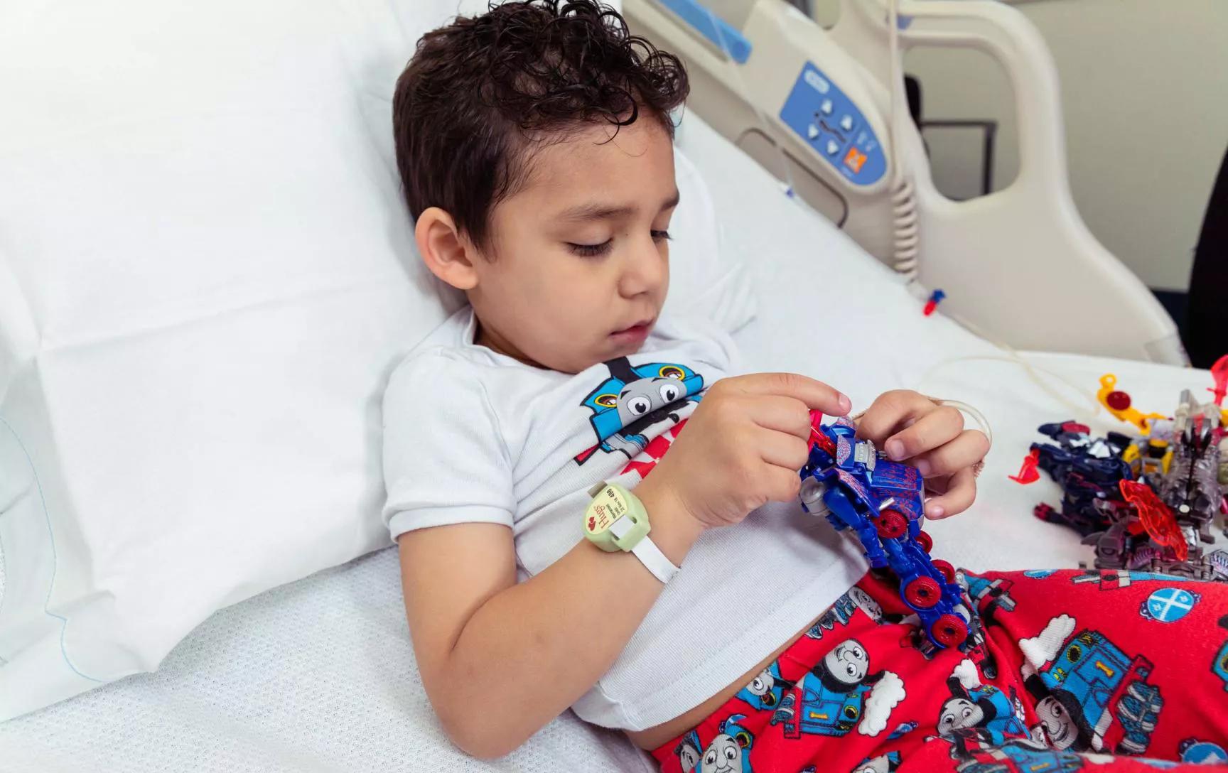 Young boy laying in hospital bed wearing the Hugs Infant Protection solution band around his wrist