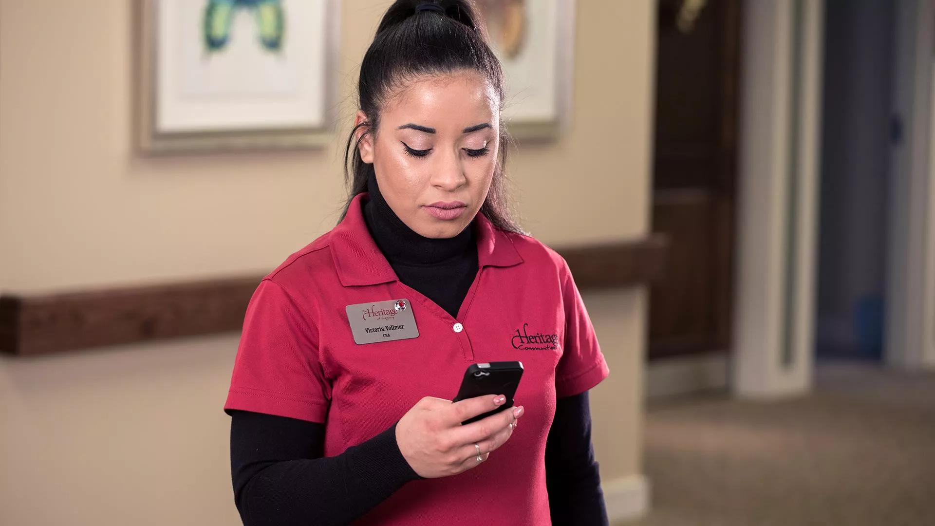 Senior Living caregiver checking the Securitas Healthcare Arial mobile application on her smartphone