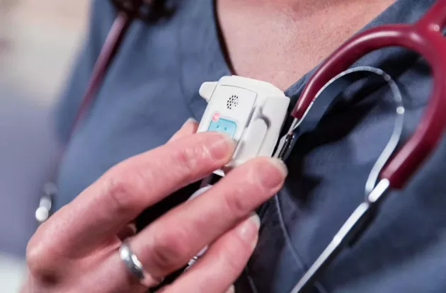 Caregiver pressing the alert button on the Securitas Healthcare T14 Staff Protection badge.