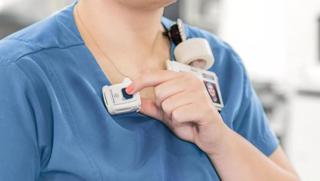 Nurse pressing button of Securitas Healthcare staff protection tag to call for assistance